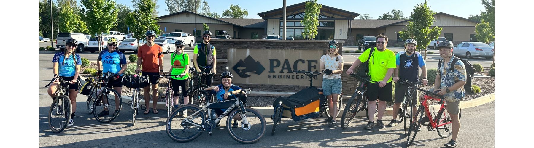 Happy riders with and without bikes smile in front of a sculpture of a bear. 
