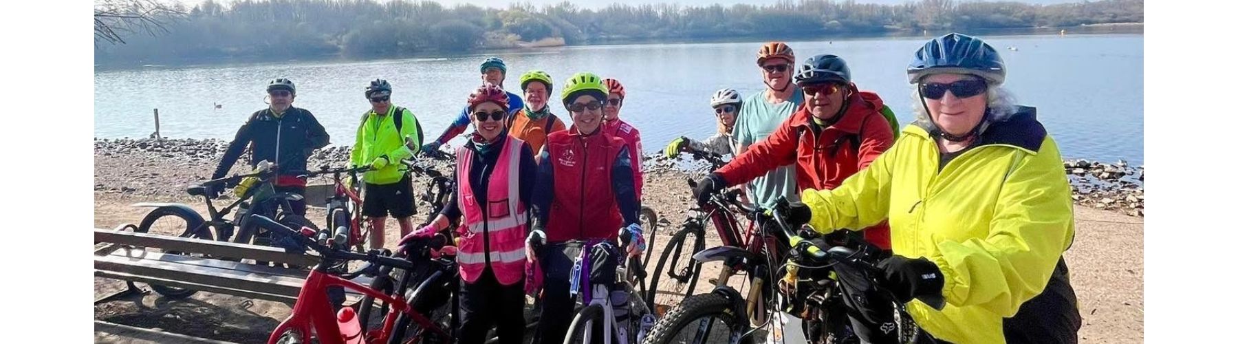 Happy riders with and without bikes smile in front of a sculpture of a bear. 