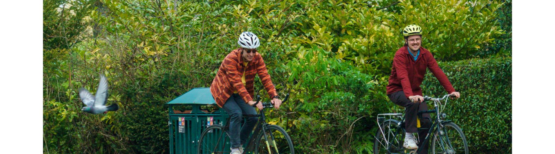 Happy riders with and without bikes smile in front of a sculpture of a bear. 